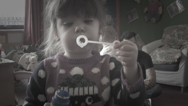 A young girl blows bubbles.