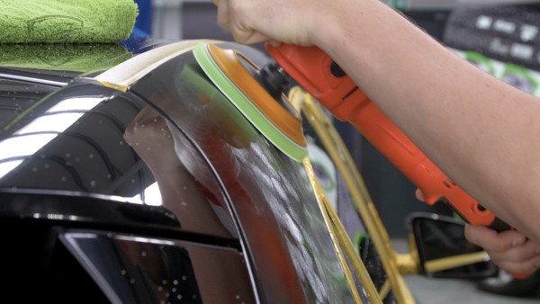 Car being polished with an electric polishing machine.