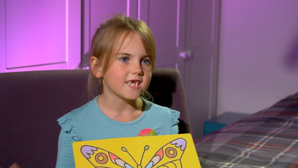 Child shows off her butterfly sand picture.