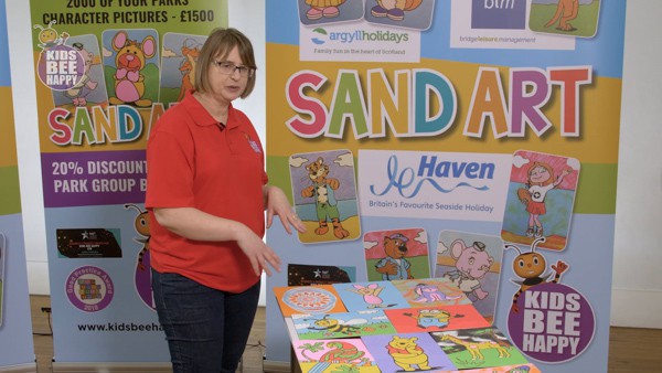 A woman show how to present sand art artwork.